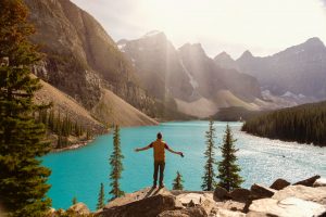 a man standing on the cliff over a lake